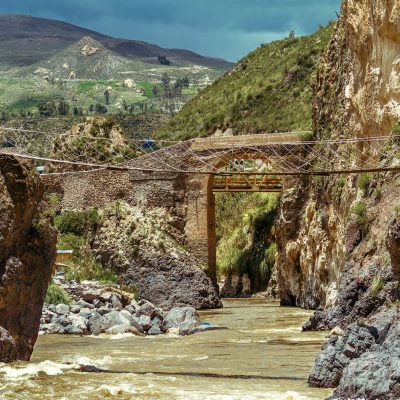 Suspension bridge and stone bridge over rapids of the Colca River in Peru